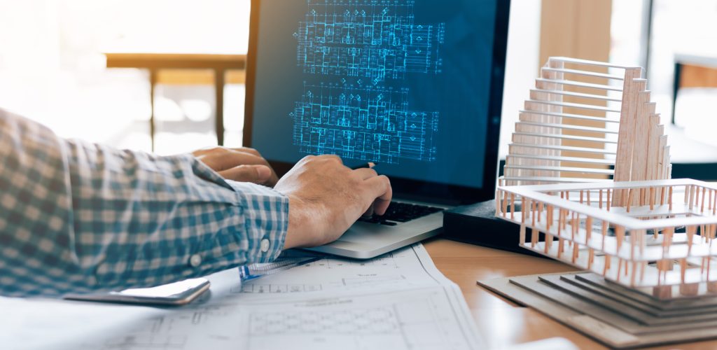 Architect using laptop and sitting in modern office working blueprint project.